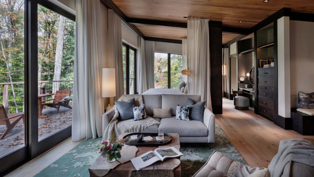 The sitting area with a bedroom behind it and a deck in the woods in one of the Treehouses at Twin Farms