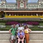 Dave Parfitt and his family, including kids and his wife, who uses a wheelchair, posing in front of Disney World Magic Kingdom train station