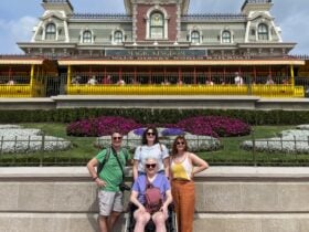 Dave Parfitt and his family, including kids and his wife, who uses a wheelchair, posing in front of Disney World Magic Kingdom train station
