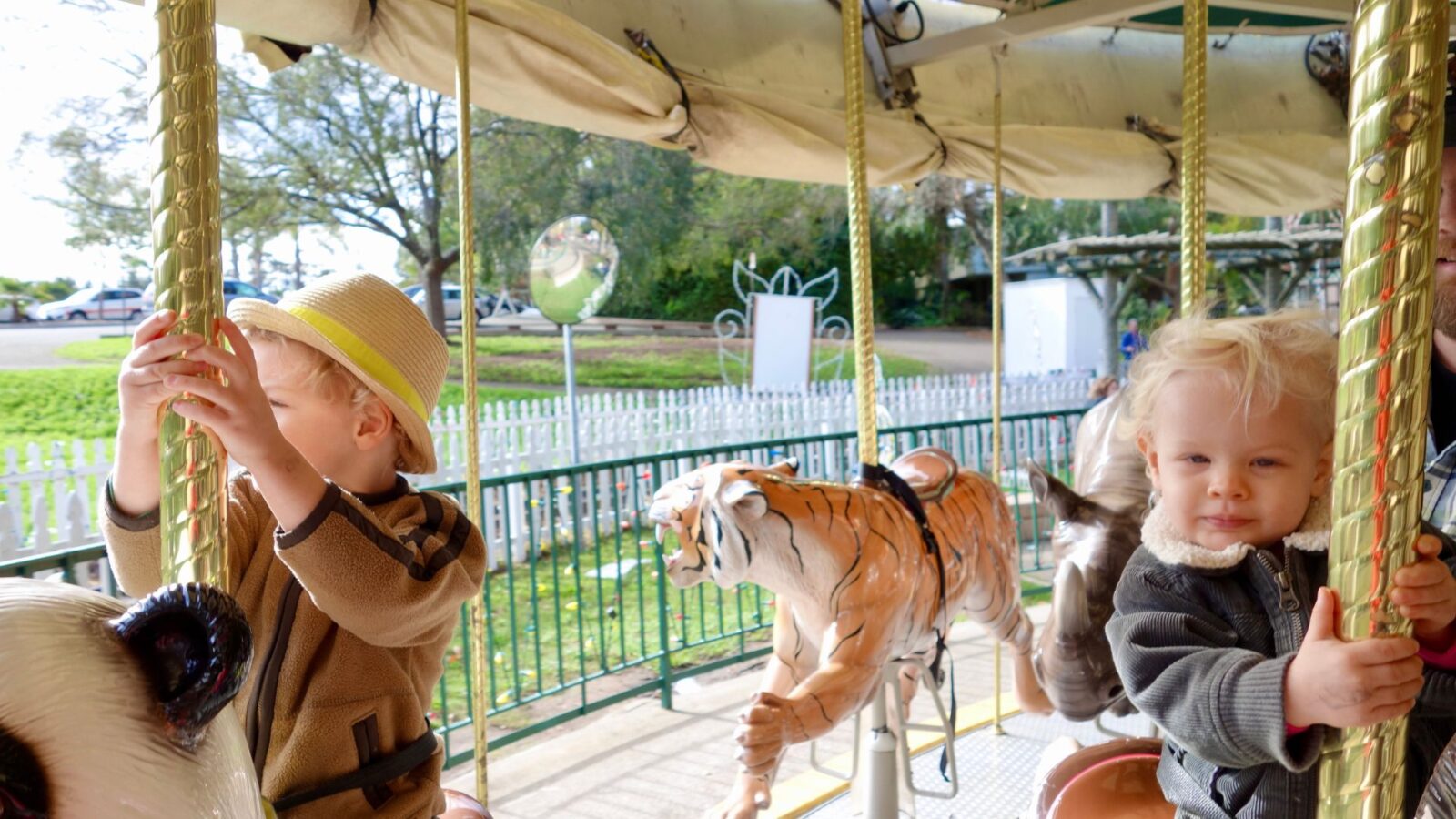 a baby and a toddler riding a carousel at the Oakland Zoo in California