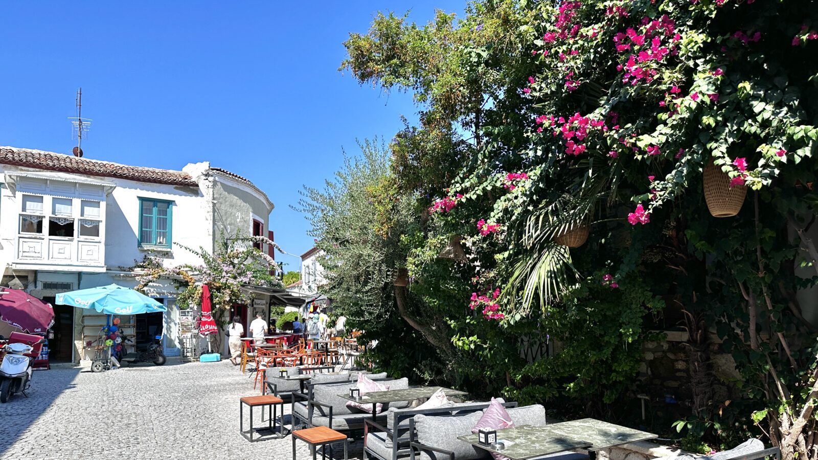 alacati street with tables and blooming vines