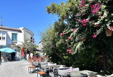 alacati street with tables and blooming vines