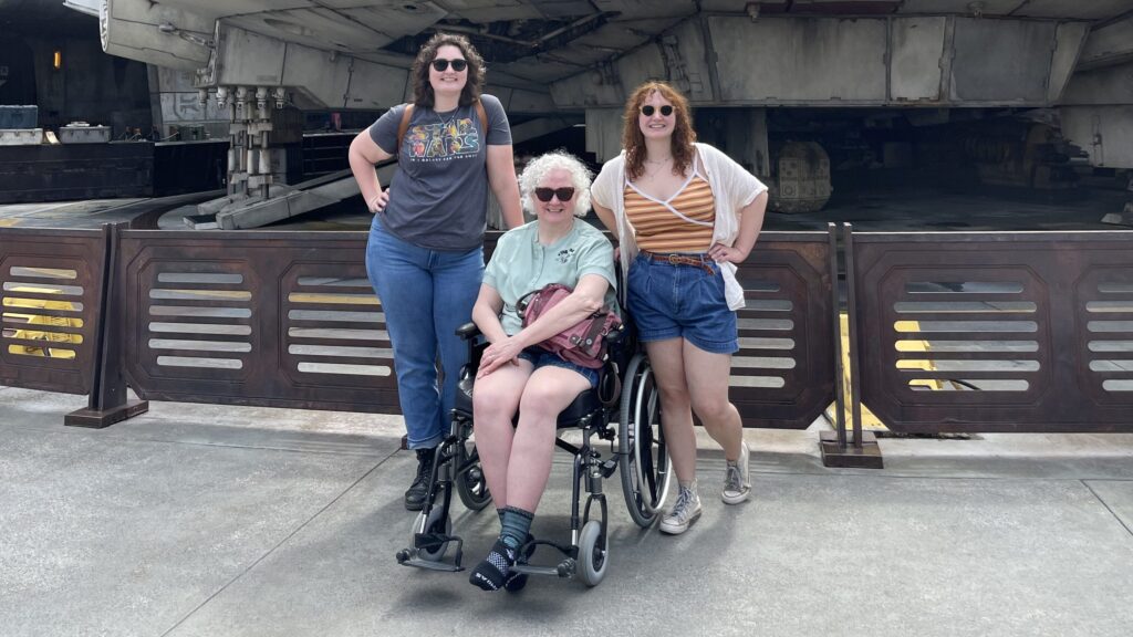 Family including a parent in a wheelchair in front of the Millennium Falcon at Disney