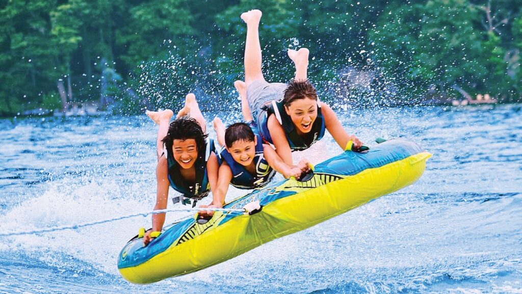 Three kids on a tube being pulled by a boat at Candlewood Lake in Connecticut