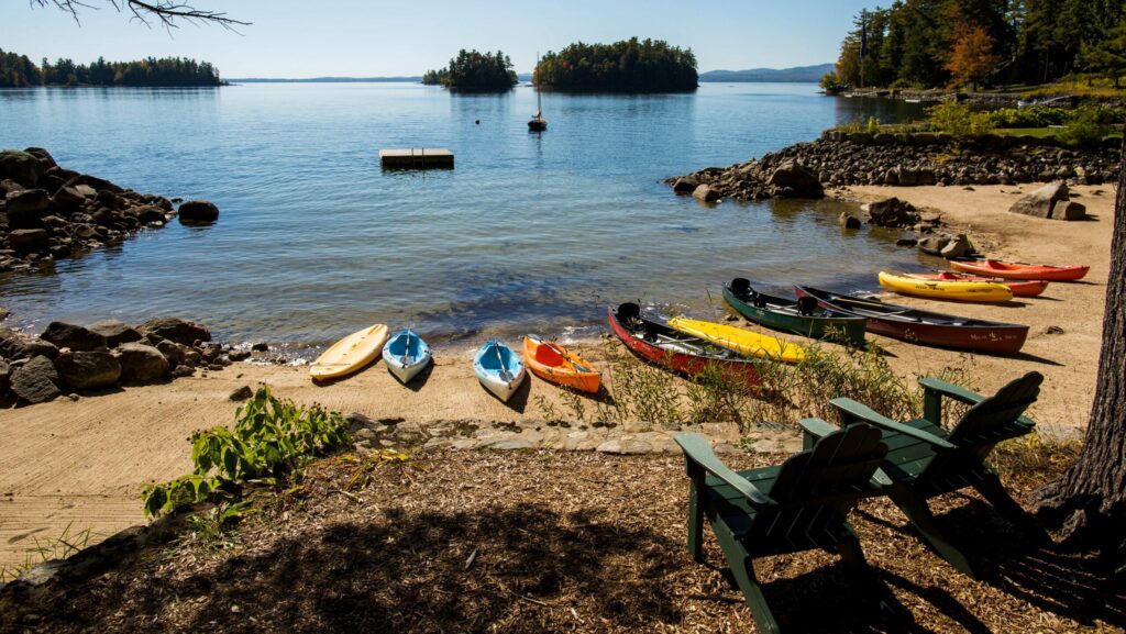 Kayaks and canoes sitting by Sebago Lake at Migis Lodge