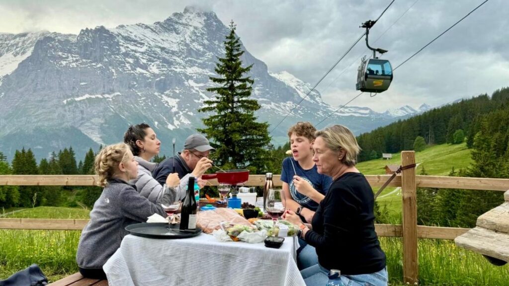 family around a picnic table eating fondue in Switzerland