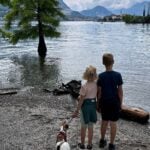 two kids and a dog look out from Isola Bella to Isola dei Pescatori on Lake Maggiore in the Italian lake district