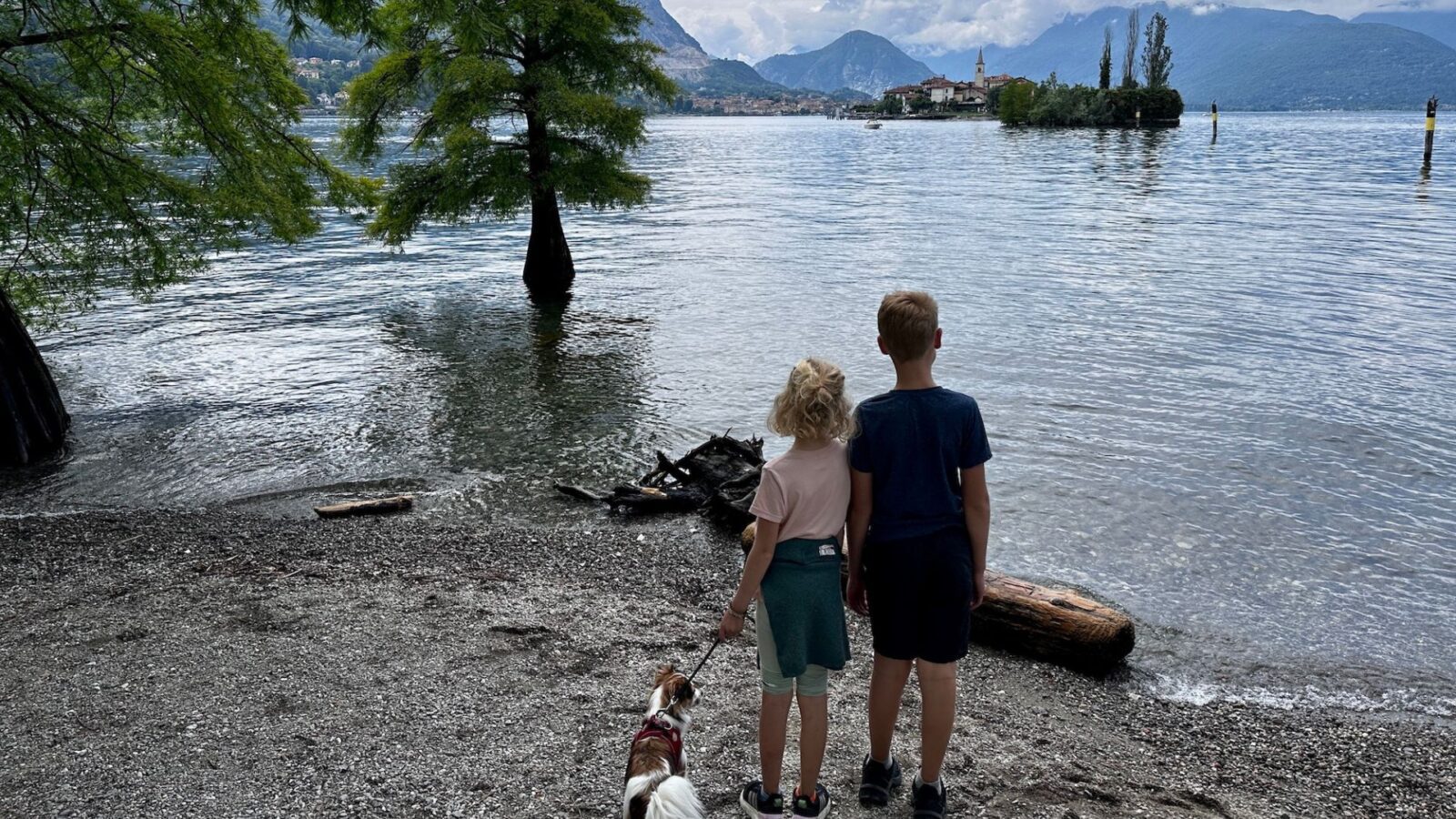 two kids and a dog look out from Isola Bella to Isola dei Pescatori on Lake Maggiore in the Italian lake district