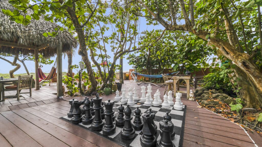 A giant chess board on a wooden outdoor deck with hammocks at Beach Place Guesthouses