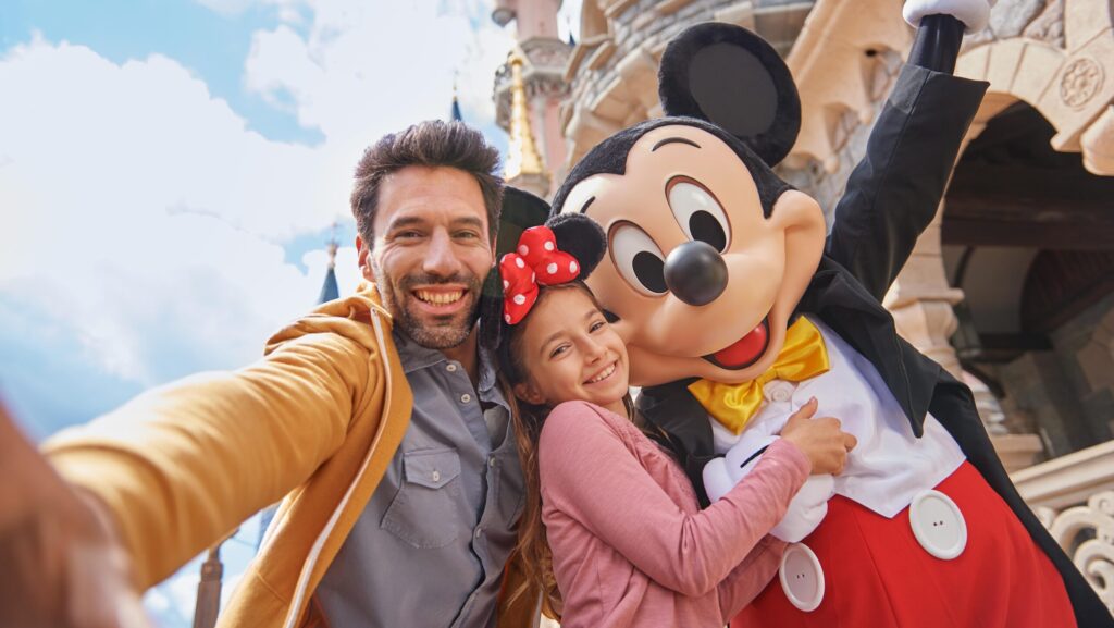 An adult and child taking a picture with Mickey Mouse at Disneyland Paris