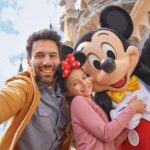 An adult and child taking a picture with Mickey Mouse at Disneyland Paris