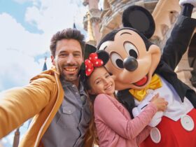 An adult and child taking a picture with Mickey Mouse at Disneyland Paris