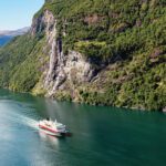 Cruise ship sailing through a mountainous village in Norway