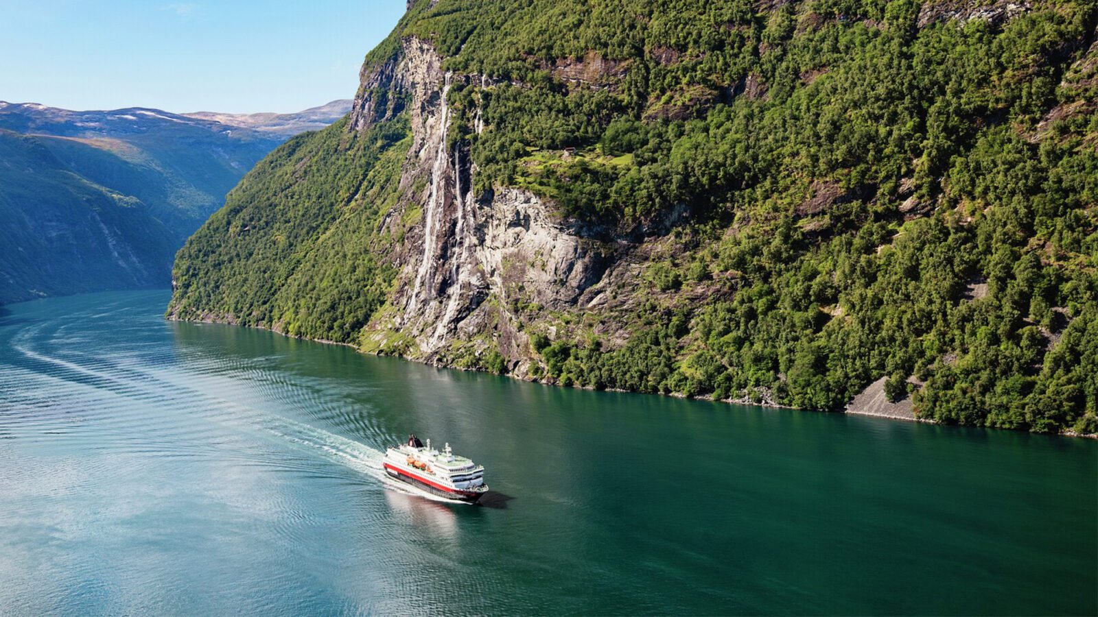 Cruise ship sailing through a mountainous village in Norway