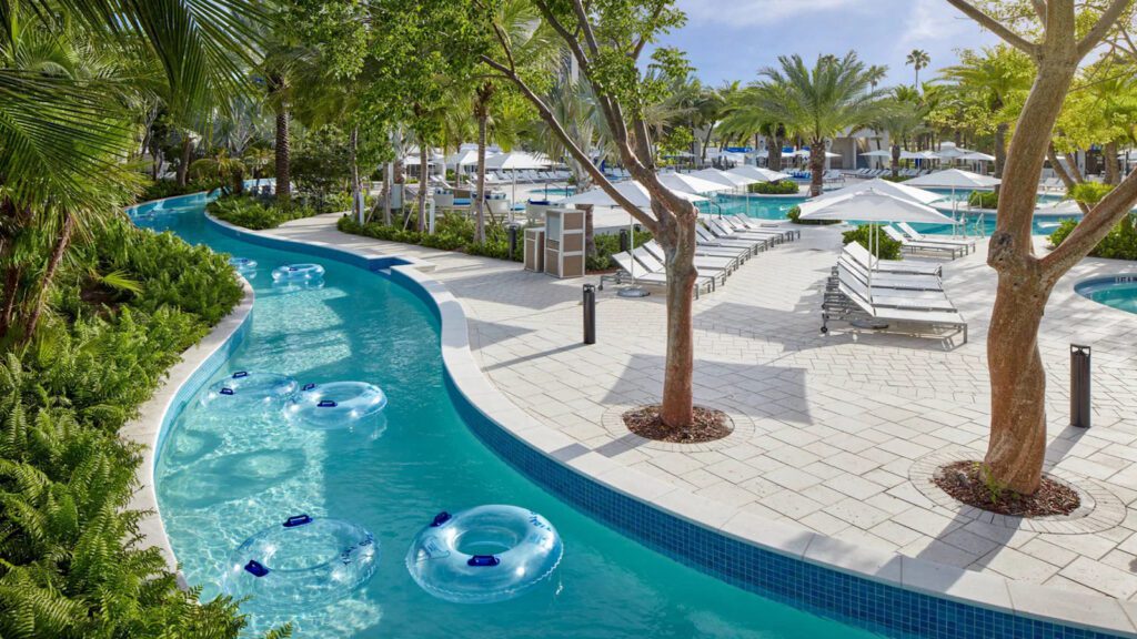 Empty tubes floating down a lazy river surrounded by trees and deck chairs