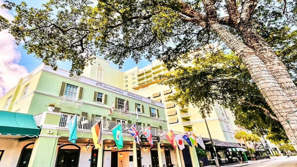 Historic hotel on tree-lined main street with flags from various countries hanging from balcony