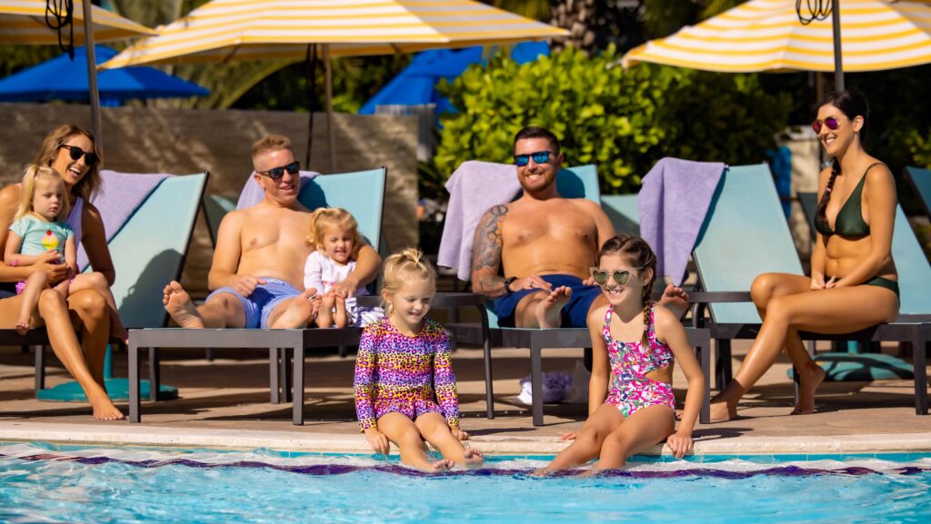 Kids sitting by the edge of a pool with their parents