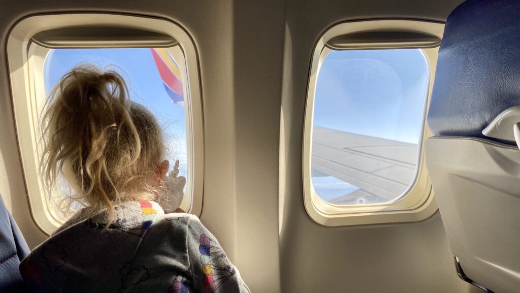 child and stuffed animal looking out window of Southwest plane