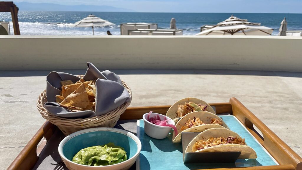 tacos on a tray with the beach in the background at Grand Velas Riviera Nayarit