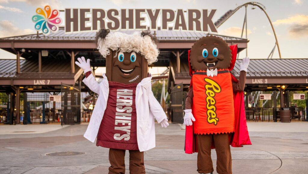 Hersheypark characters wearing Halloween costumes in front of the entrance to the park