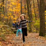 Kids running on a path through the woods during the fall