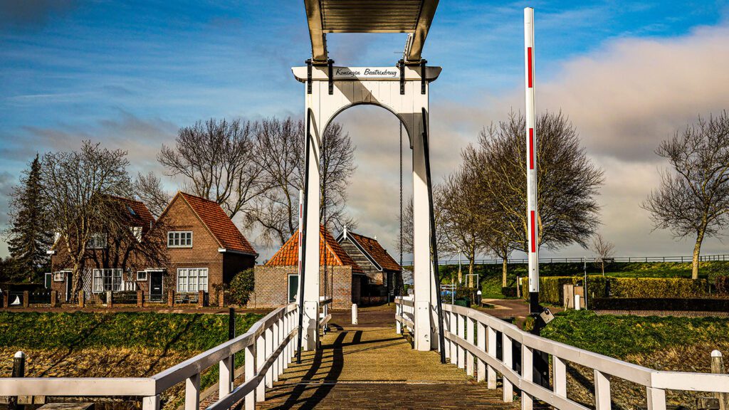 Old drawbridge leading to a small brick village with trees in the background