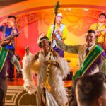 Actors dressed in New Orleans-style costumes singing and dancing on a colorful stage