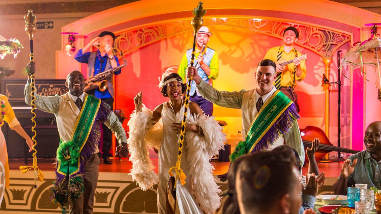 Actors dressed in New Orleans-style costumes singing and dancing on a colorful stage