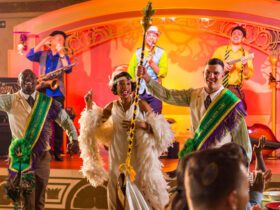 Actors dressed in New Orleans-style costumes singing and dancing on a colorful stage