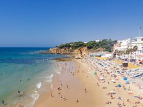 Golden san beach with turquoise water, with rocky bluff and whitewashed buildings in the background