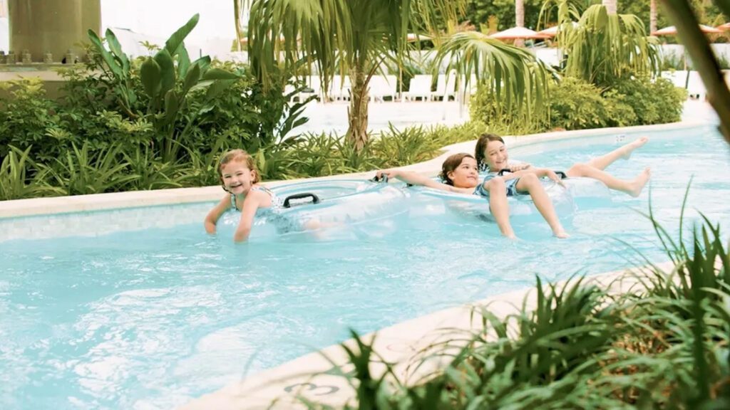 Three kids in tube floats going down a lazy river swimming pool