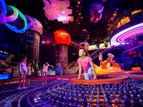 Kids play in dark, colorful space with planet structures hanging from the ceiling