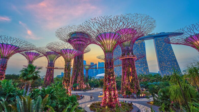 Futuristic buildings and colorful structures in a tree-lined park at sunset