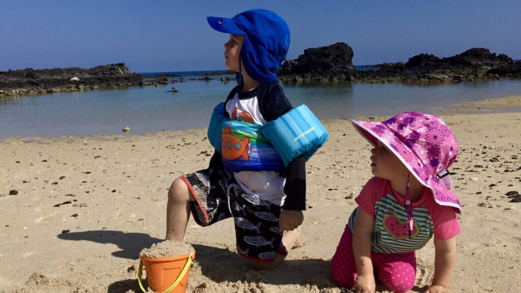 toddler and a young kid playing at the beach in Hawaii