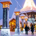 A snowy village surrounded by lanterns, a tall Christmas tree, and people walking around