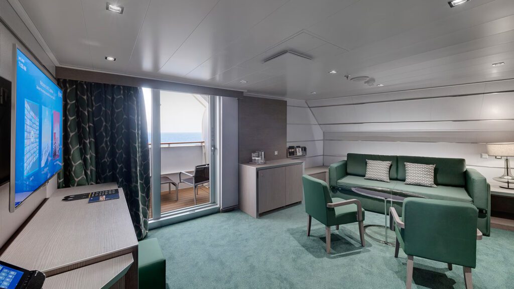 Cruise ship suite with green color scheme that shows couch with two chairs, a desk with TV and balcony