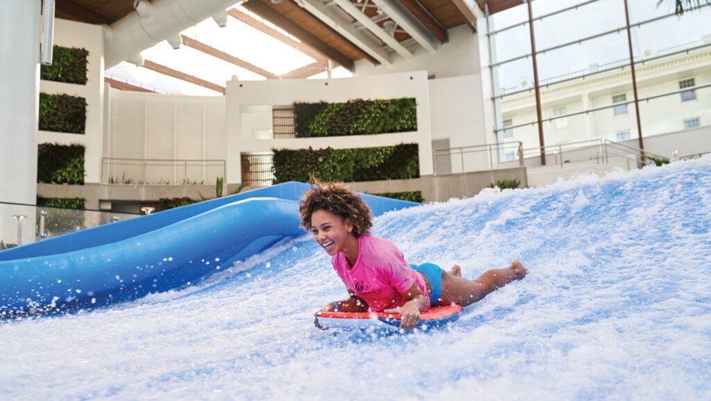 A girl on a wave simulator at an indoor water park