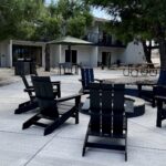 courtyard at Field Station Joshua Tree with campfire ring, Adirondack chairs, and picnic tables