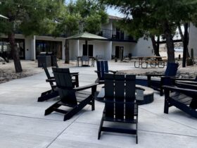 courtyard at Field Station Joshua Tree with campfire ring, Adirondack chairs, and picnic tables