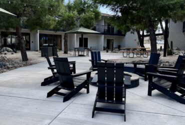 courtyard at Field Station Joshua Tree with campfire ring, Adirondack chairs, and picnic tables