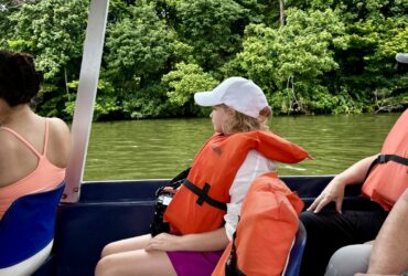 child on a Trafalgar tour of Costa Rica looking out from a seat on a boat in Tortuguero National Park