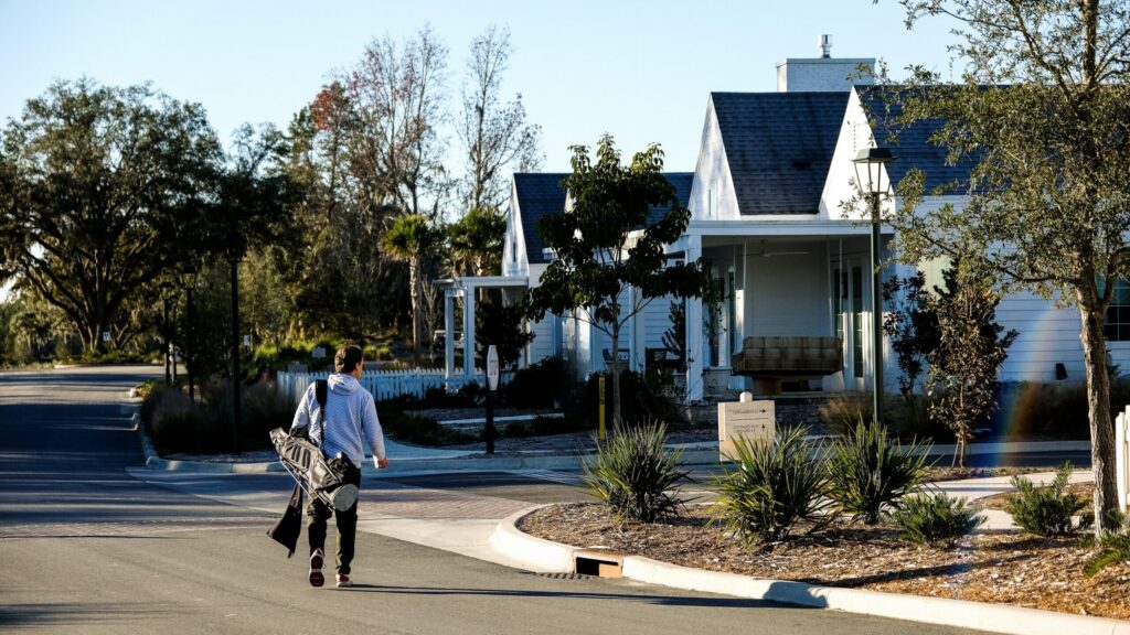 Man walking down the street carrying a golf bag