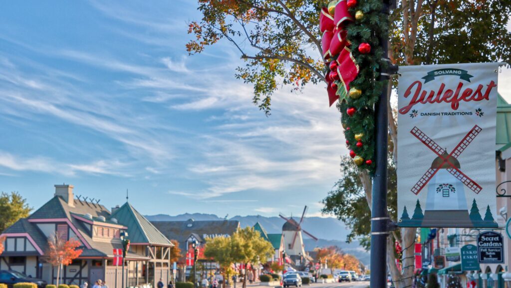 A sign for the Solvang Julefest by a street scene of the Danish-inspired town