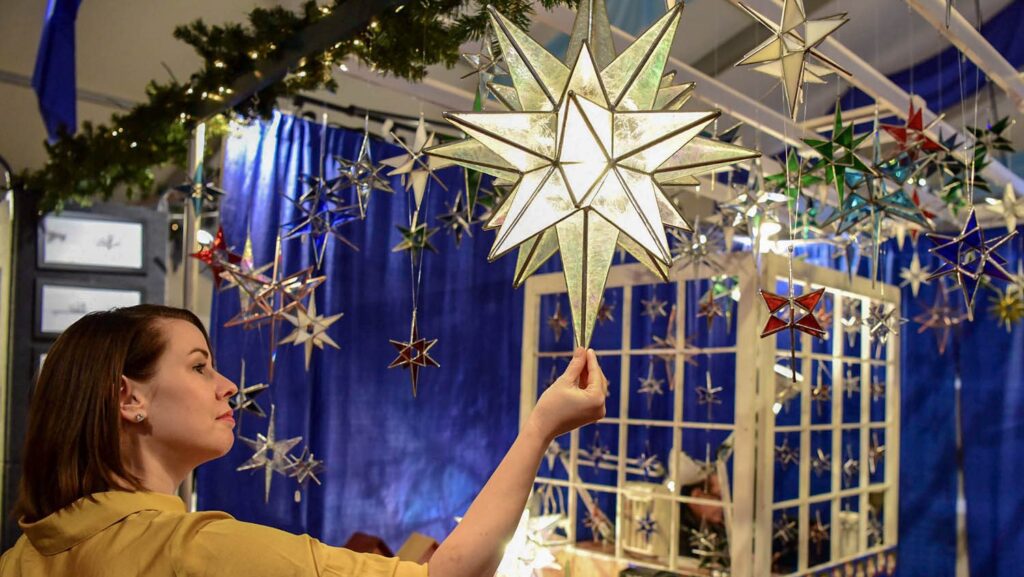 A woman looking at Moravian stars at a Christmas market