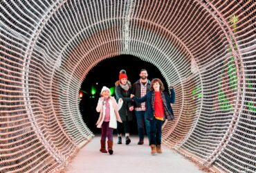 A family walking through a lighted tunnel at Calloway Resort & Gardens
