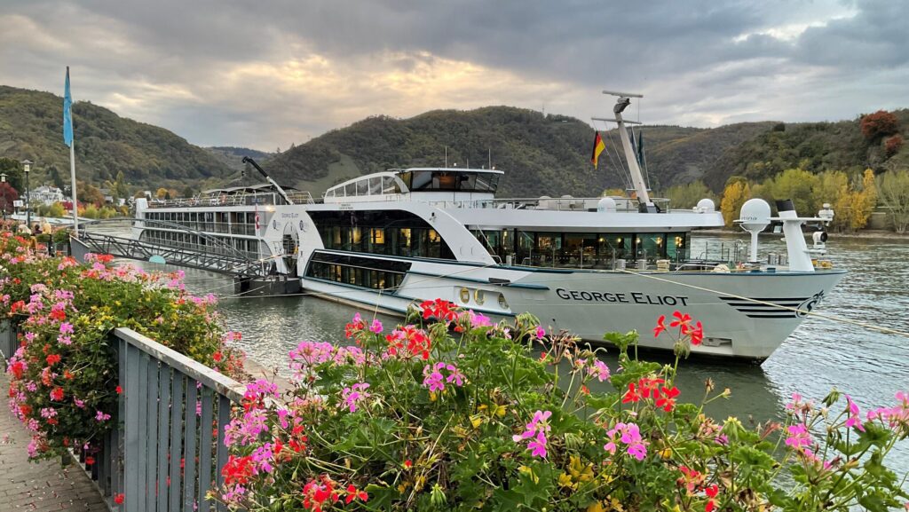 River cruise ship docked near flowers.