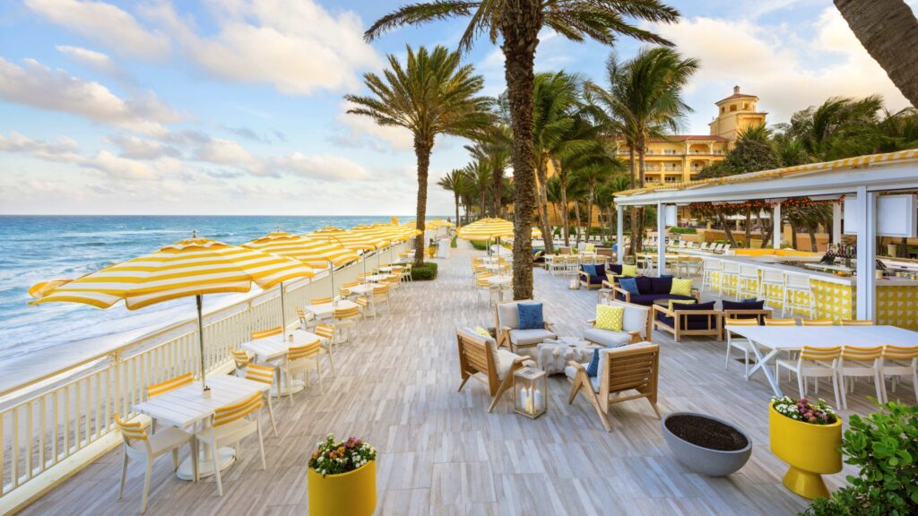 A beachfront restaurant with yellow umbrellas and palm trees in Palm Beach, Florida