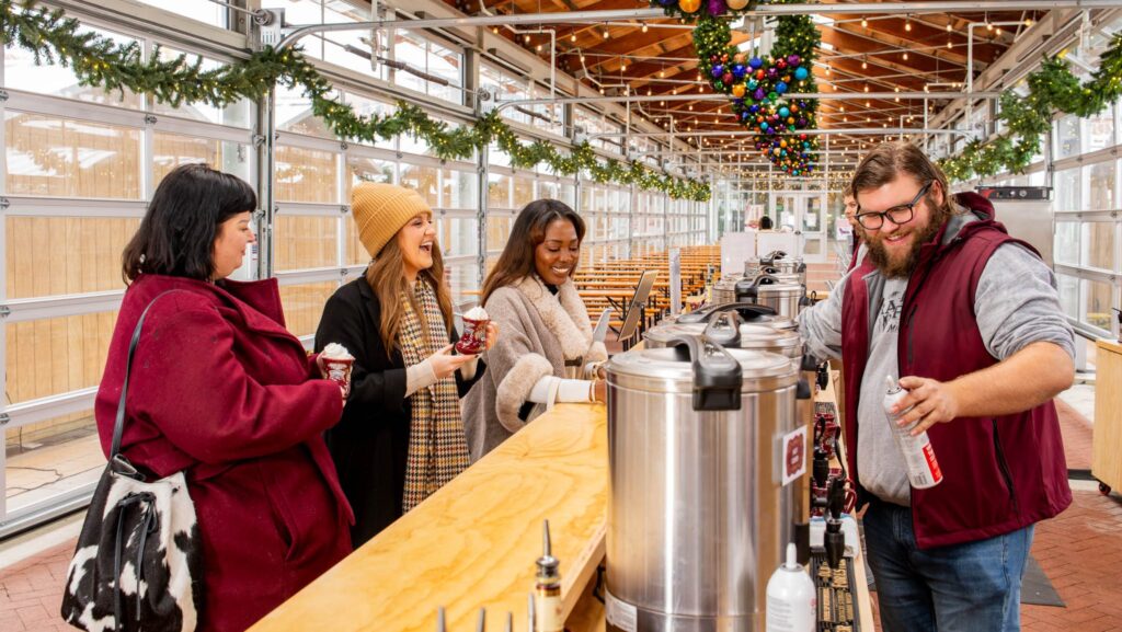 Three people getting hot beverages from a worker at the Christkindl Markt in Grand Rapids