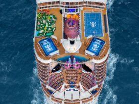 Top deck of cruise ships sailing in ocean, with a sports court, slide, surf simulators, and other features