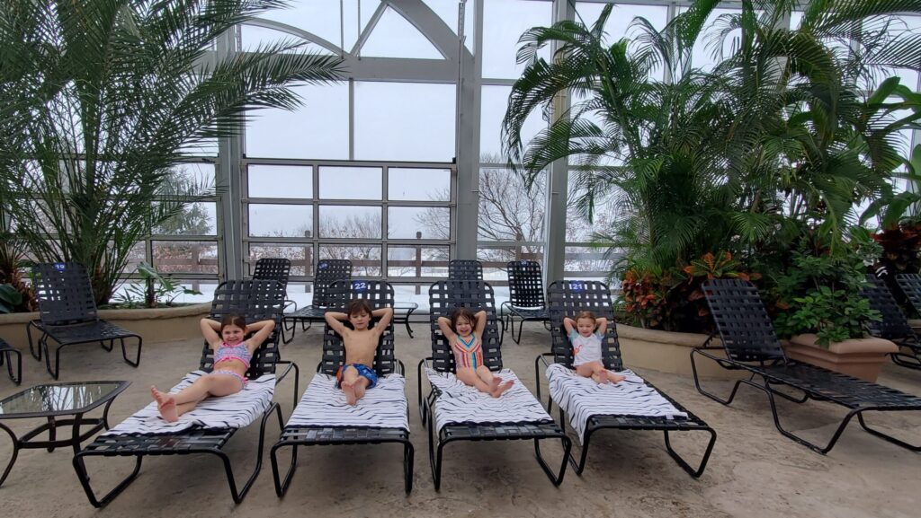 Four kids relaxing on lounge chairs at an indoor pool at Crystal Springs Resort